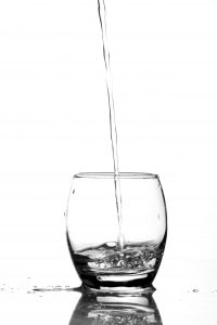 Refreshing image of water being poured into a glass, emphasizing purity and clarity.